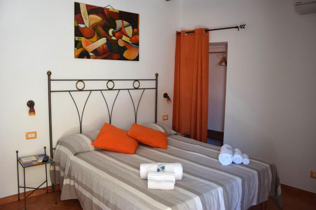 a bedroom with a bed with orange pillows and a painting at La Casa del Geko in Cefalù