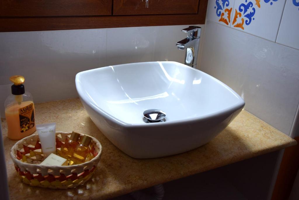 a white sink sitting on top of a counter with a bowl at La Casa del Geko in Cefalù