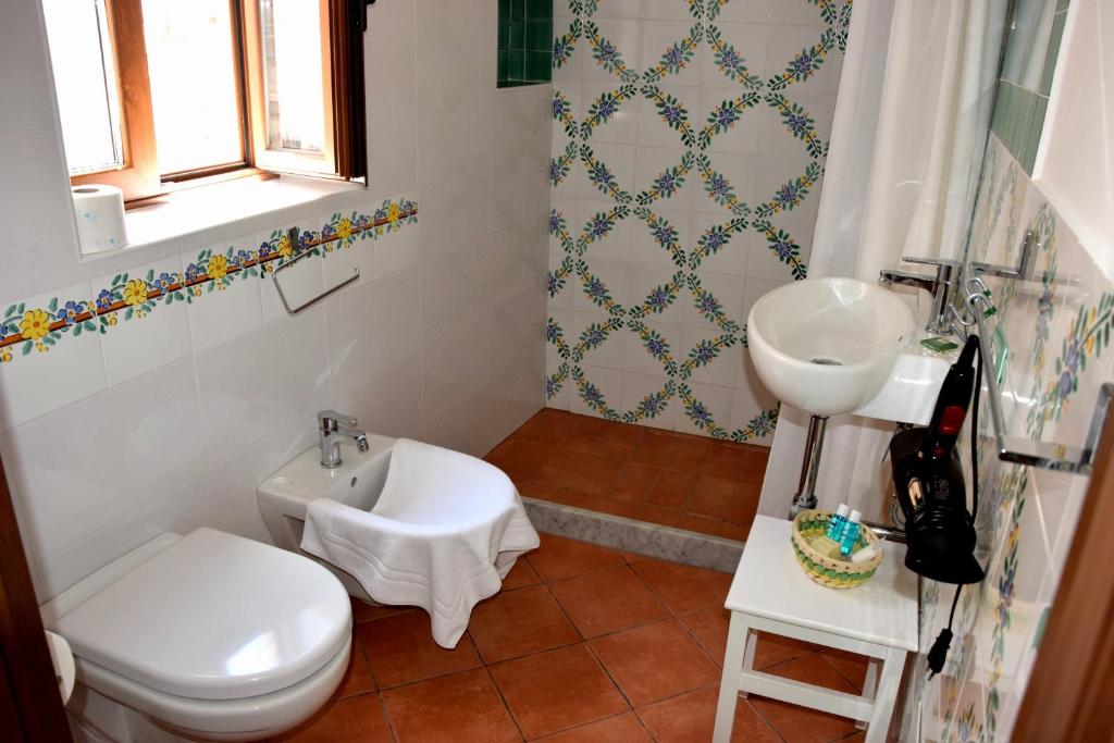 a bathroom with a white toilet and a sink at La Casa del Geko in Cefalù