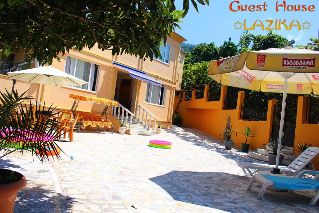 a guest house with a patio with chairs and an umbrella at Guest House Lazika in Sarpi