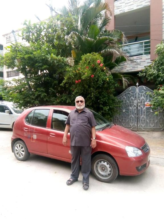 een man die voor een rode auto staat bij Home Nest in Hyderabad