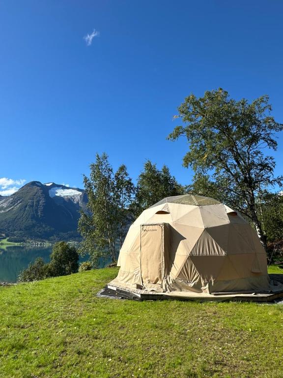 a tent on a grassy hill with a mountain in the background at Vollsnes Glamping in Stryn