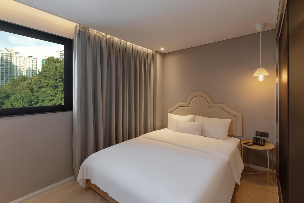 a bedroom with a white bed and a window at NewCZ Gwangan Hotel in Busan