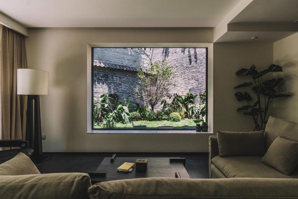 a living room with a couch and a large window at Huguang Hidden Villa Hotel in Chongqing