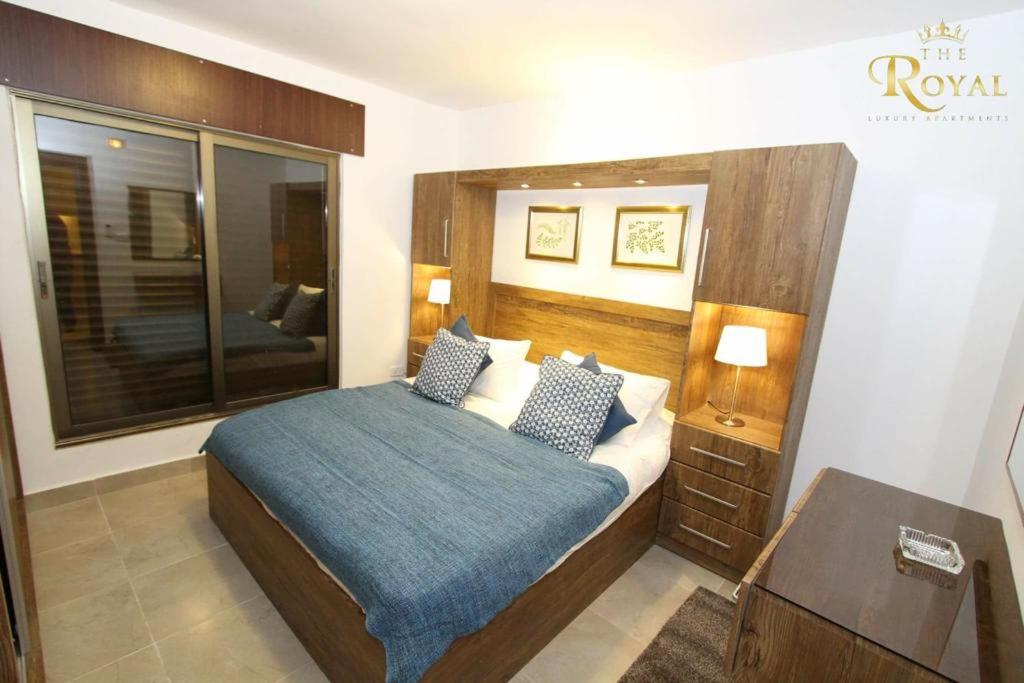 a bedroom with a bed with a wooden head board at Ammoun Luxury Apartments 1 in Amman