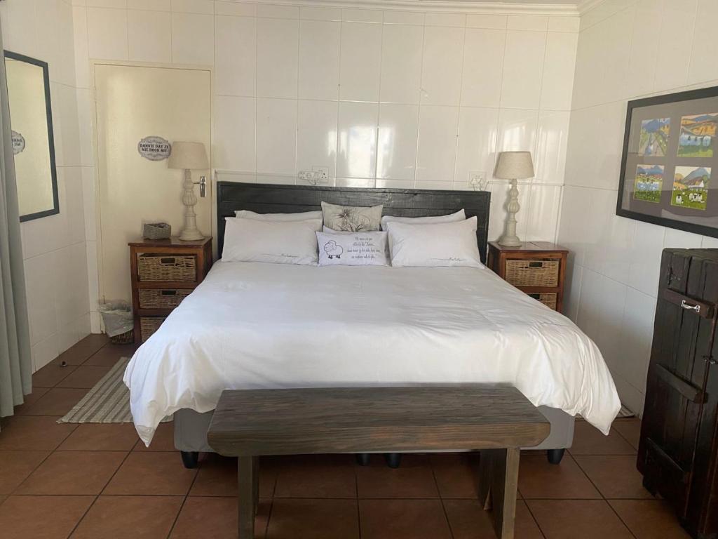 a bedroom with a large bed with white sheets and pillows at Karoo Huisie in Vanderbijlpark
