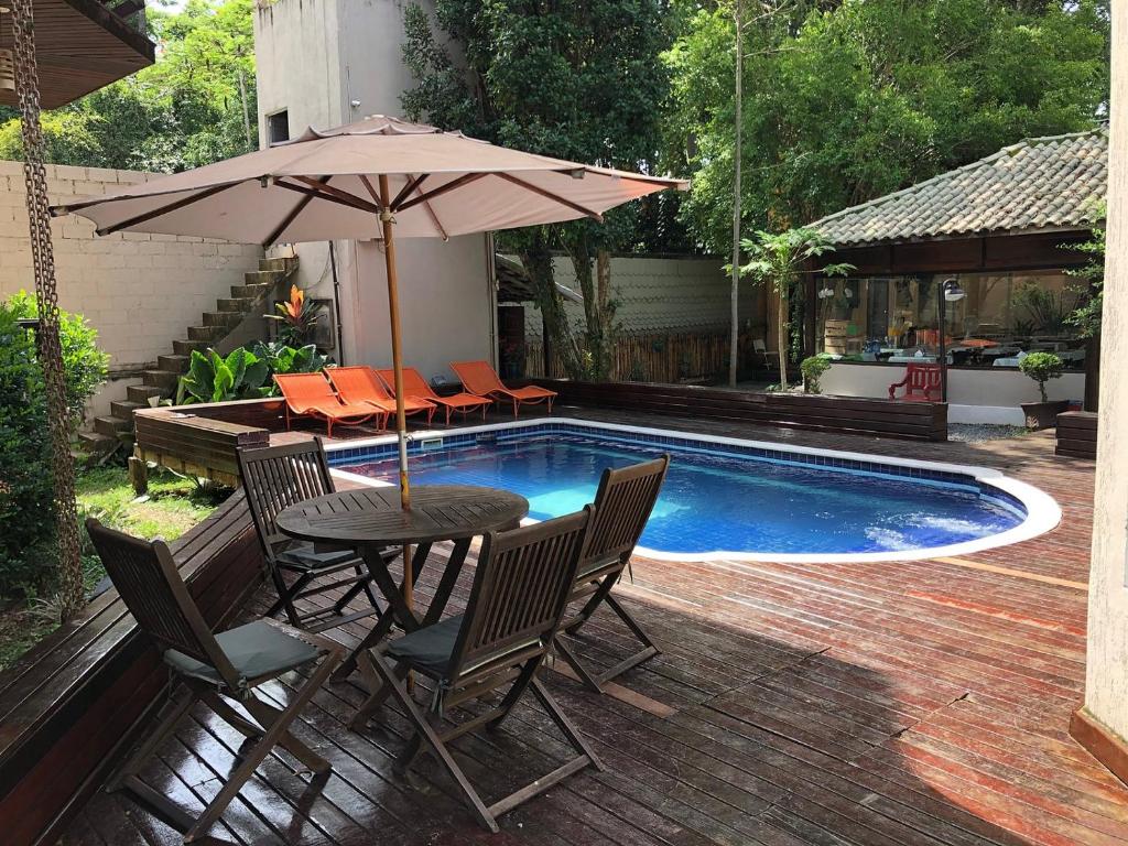 a table with an umbrella next to a swimming pool at Chale Penedo no Centro com Piscina,Hidro e Sauna ! in Itatiaia