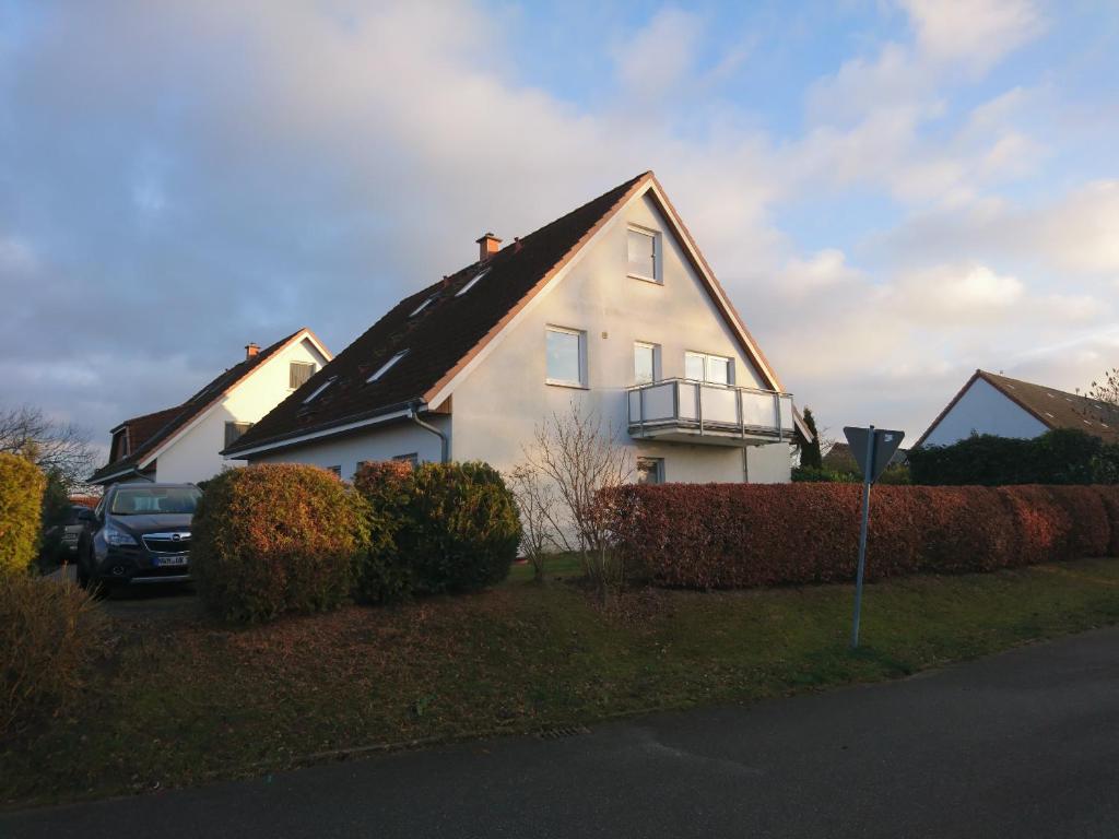 a white house with a black roof at Ostseewohnung Weiße Wiek in Hohenkirchen