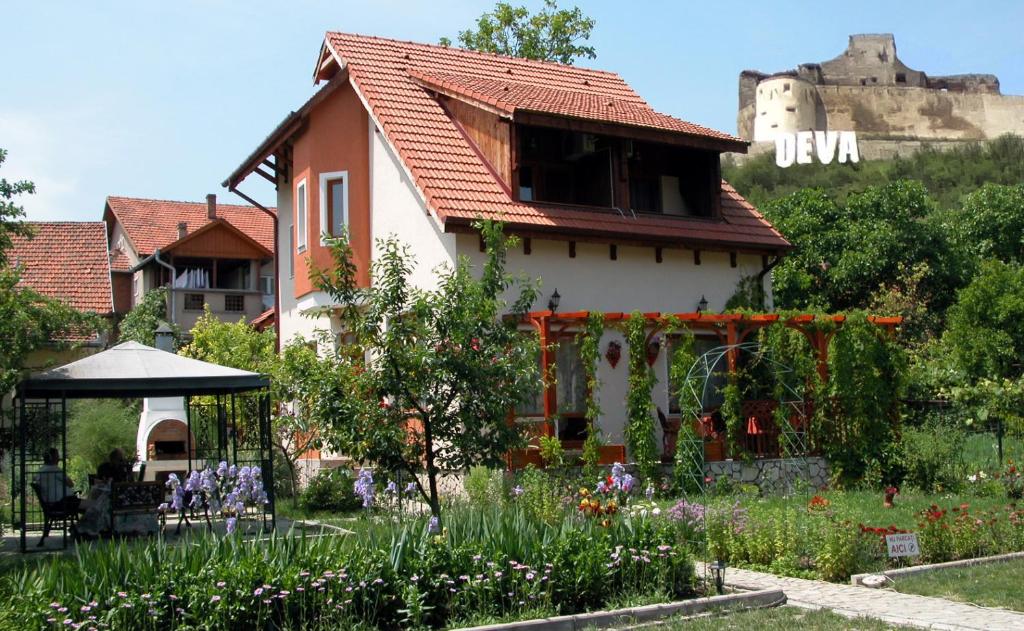 a house with a garden and a castle in the background at Pensiunea Sub Cetate Deva in Deva