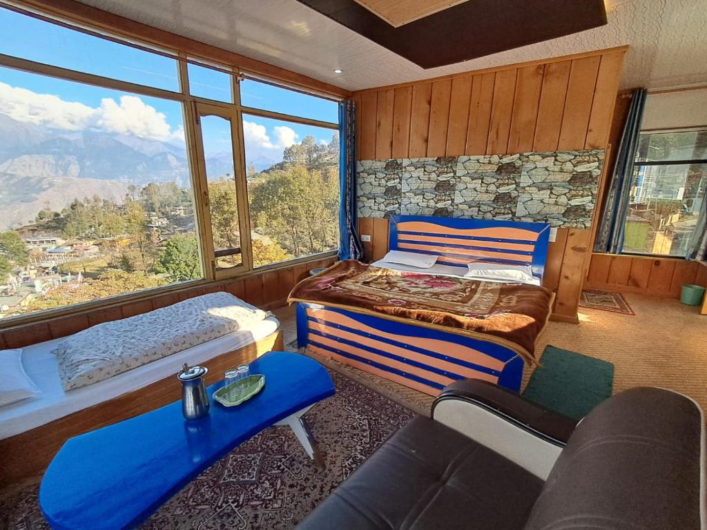 a bedroom with two beds and a large window at Hotel Pandey Lodge By StayApart in Munsyari