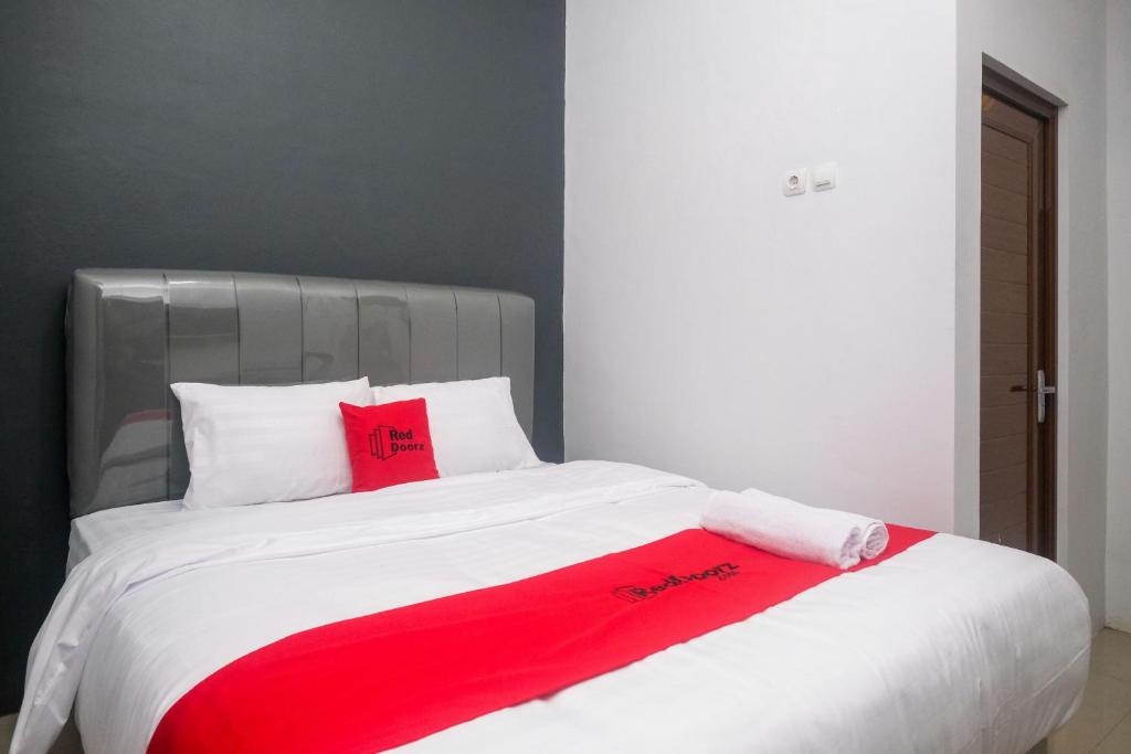 a bed with a red blanket on top of it at RedDoorz Syariah near UNIMUS Semarang in Alastuwo