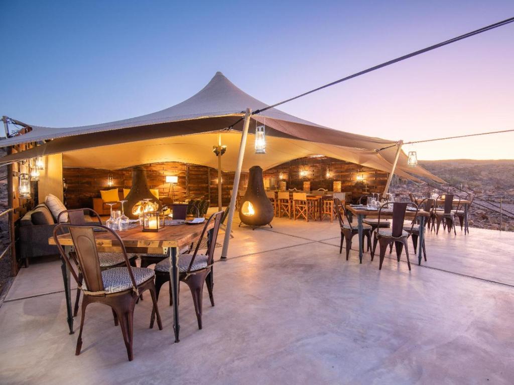 a tent with tables and chairs on a patio at Camp Doros in Twyfelfontein