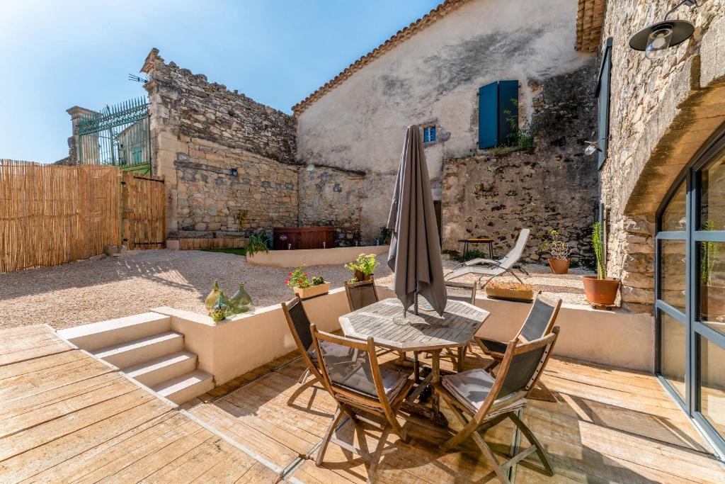 une terrasse avec une table, un parasol et des chaises dans l'établissement La Grangerie, à Moulézan