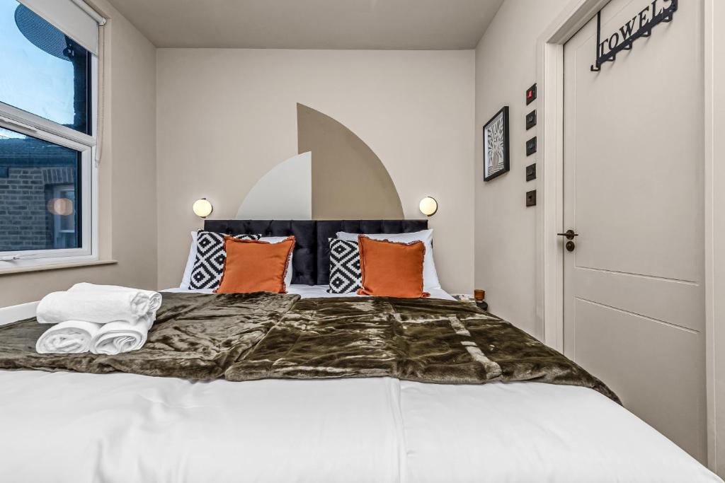 a bedroom with a large bed with orange pillows at Consort 3A- 4 | Stylish Compact Studio with Kitchennette and Full Communal Kitchen in London
