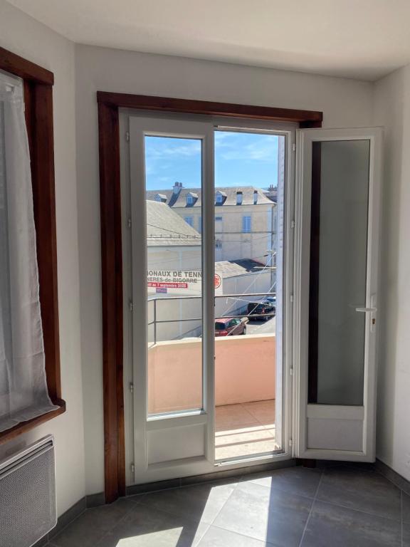 a sliding glass door with a view of a building at Appartement meublé 52m2 in Bagnères-de-Bigorre