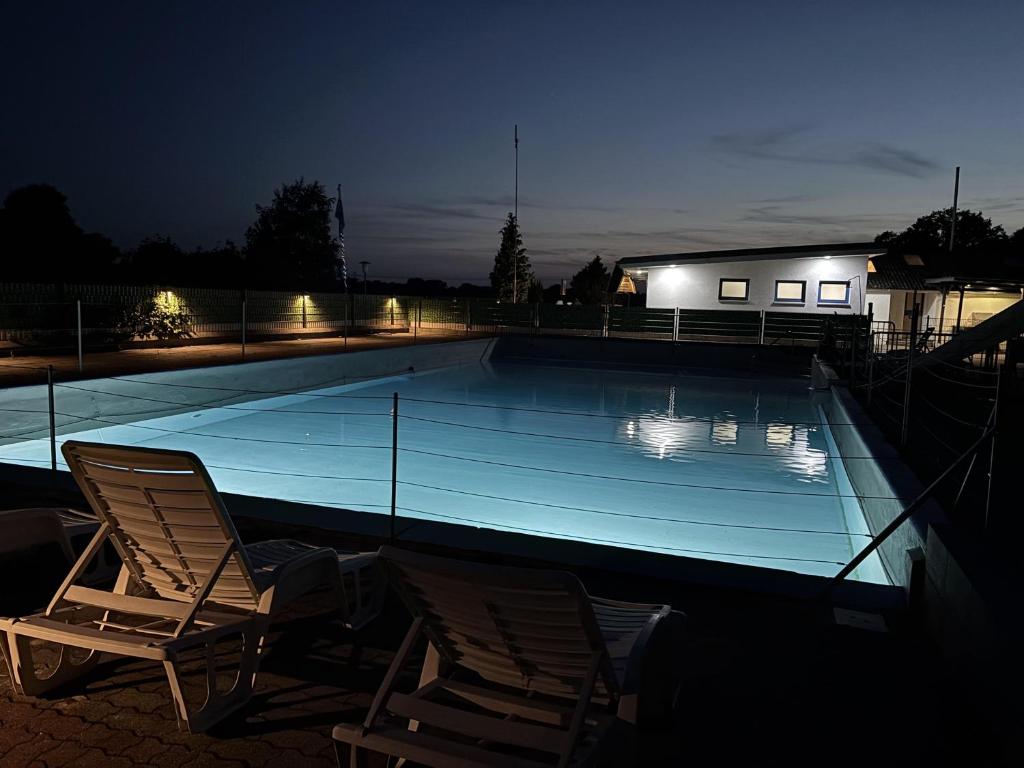 Dos sillas sentadas junto a una piscina por la noche. en Moin Camp, en Ottersberg