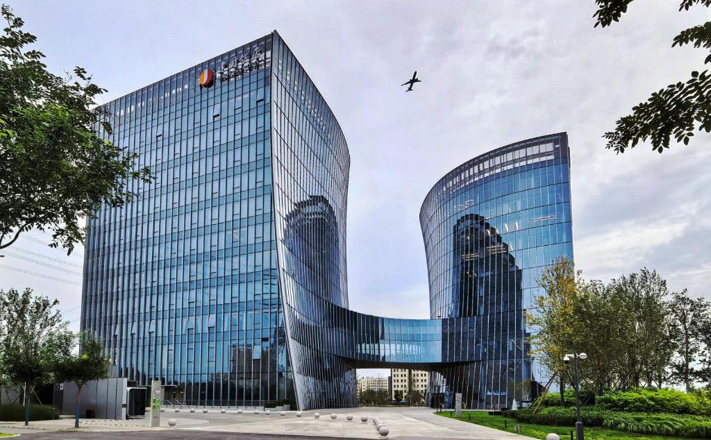 a plane flying over a tall glass building at Jianguo Hotel HUANQIU in Beijing