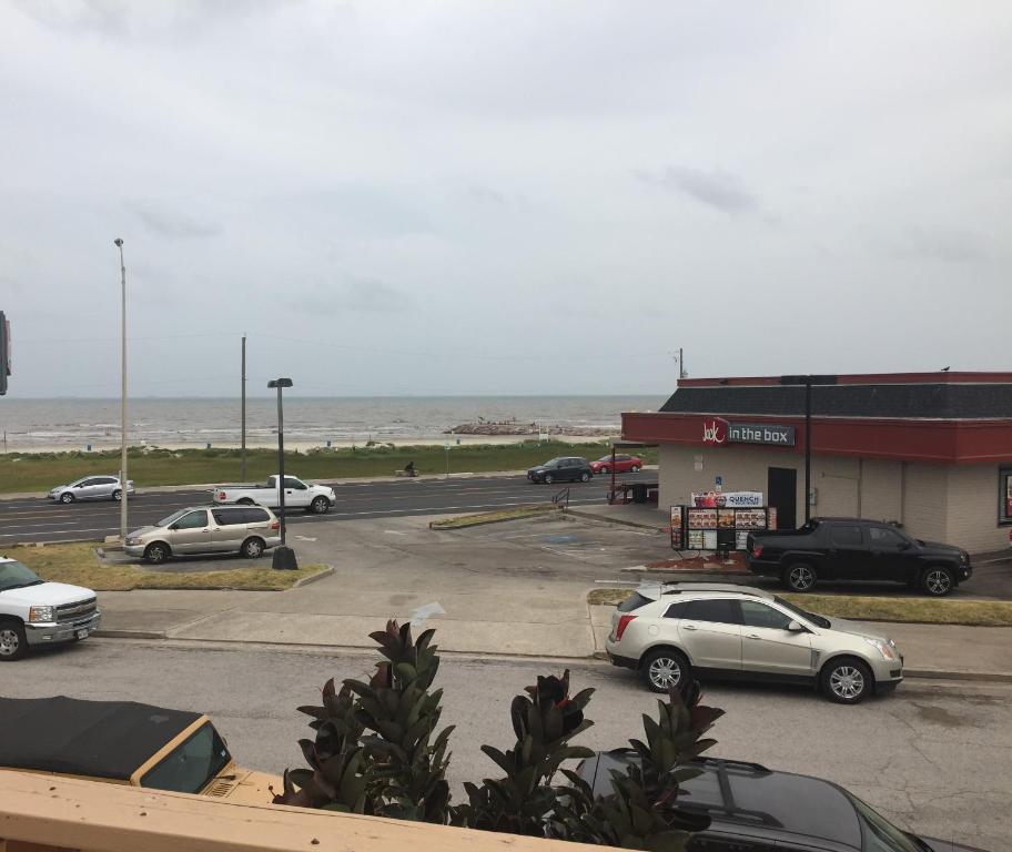 een parkeerplaats met auto's geparkeerd voor een winkel bij Surf Motel and Apartments in Galveston