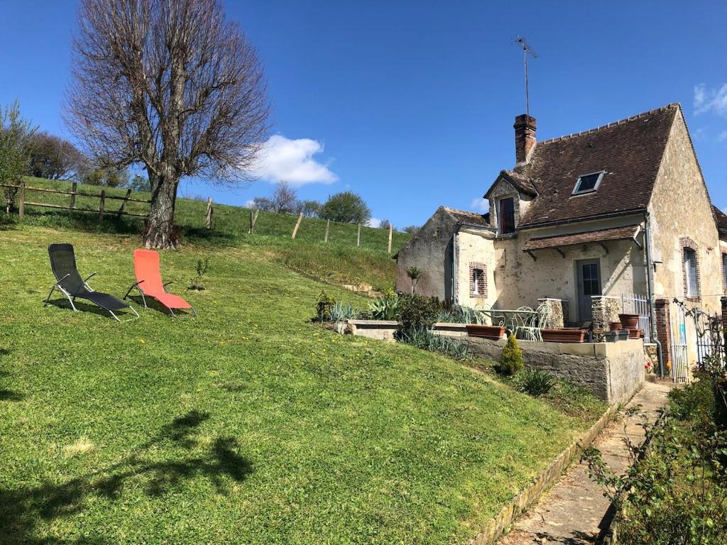 una vieja casa en una colina con césped con un árbol en Le Côtier, en Margon