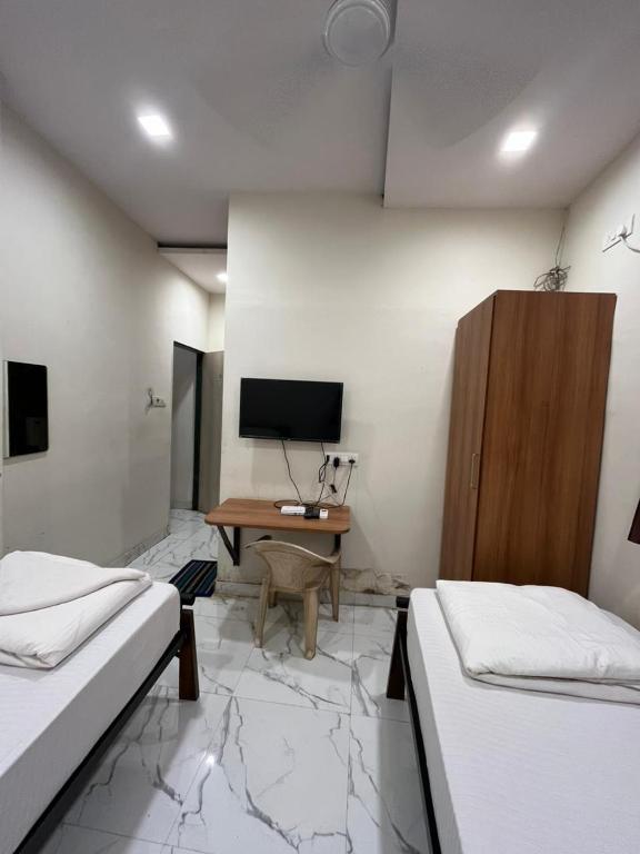 a room with two beds and a desk with a computer at Red House Hostels - POWAI HOSTELS GROUPS in Mumbai