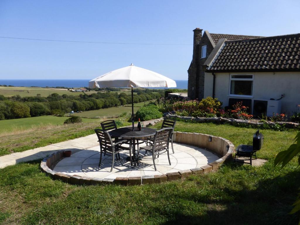 a table with chairs and an umbrella in a yard at Meadow Cottage in Scarborough