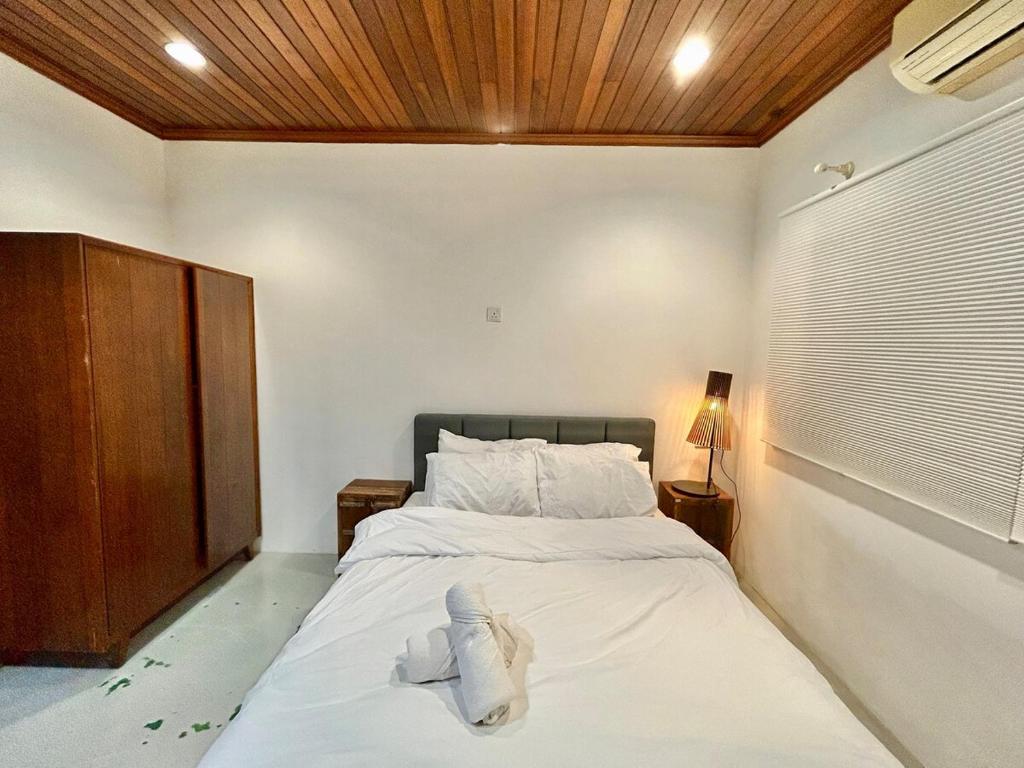 a bedroom with a bed with white sheets and a wooden ceiling at Chic Designer Bedroom in Shared Bungalow near LRT SS1 PJ in Petaling Jaya