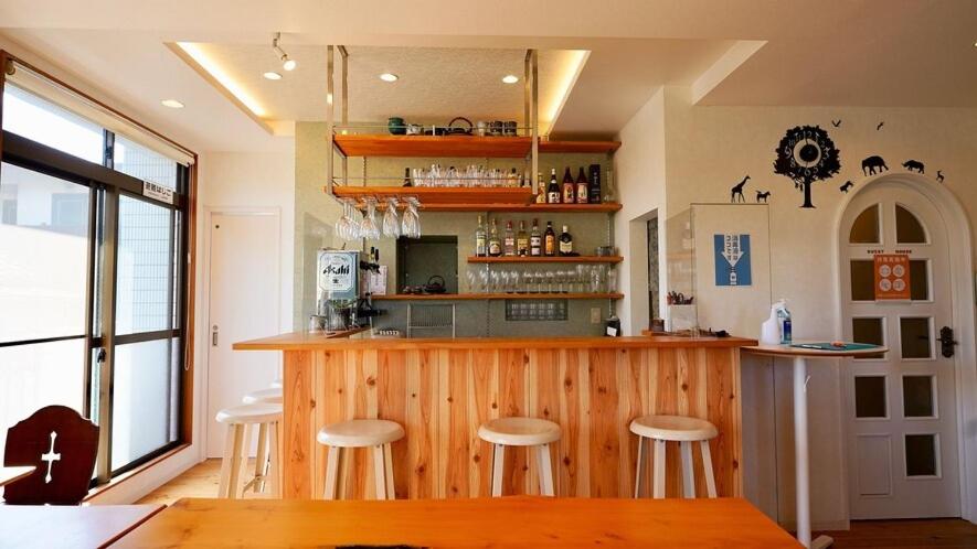a kitchen with a bar with stools in it at さくらのうえ in Kagoshima