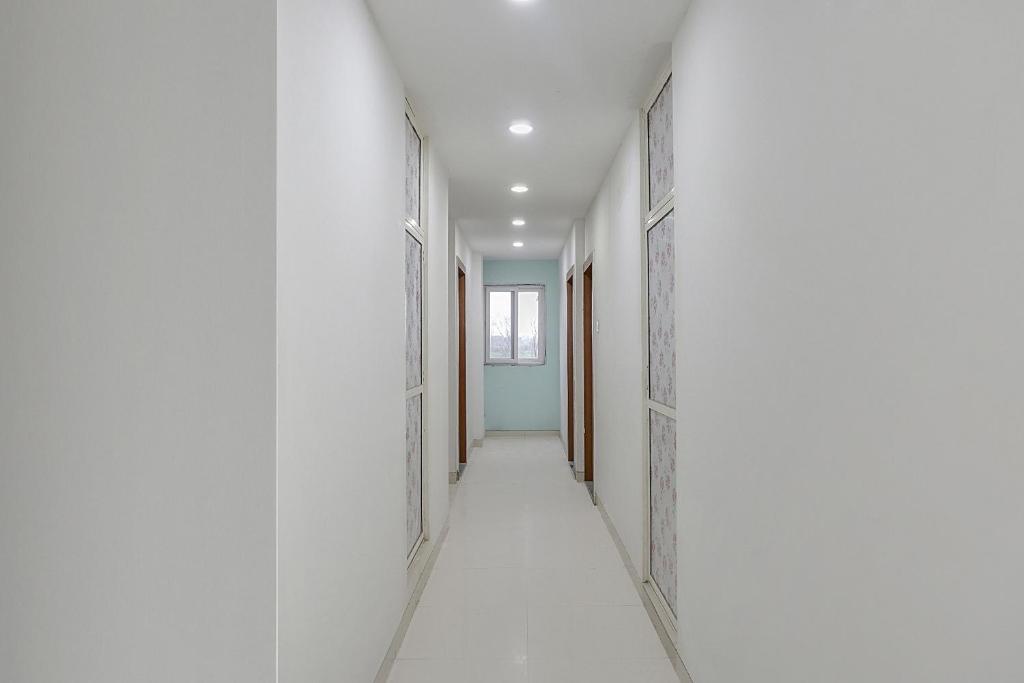 an empty corridor with white walls and an open door at Hotel O Galaxy Hospitality in Pune