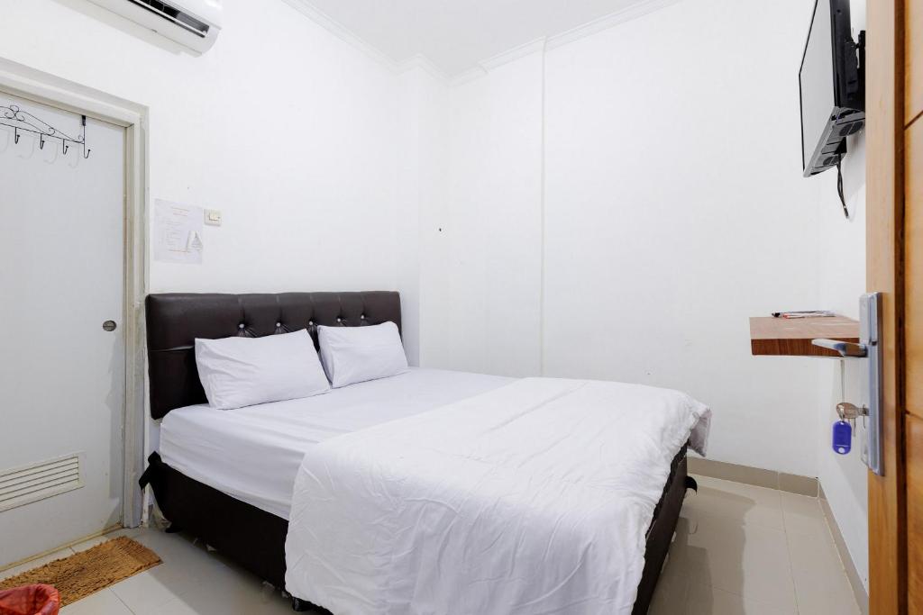 a bedroom with a bed with white sheets and pillows at JJ House Mitra RedDoorz in Jakarta
