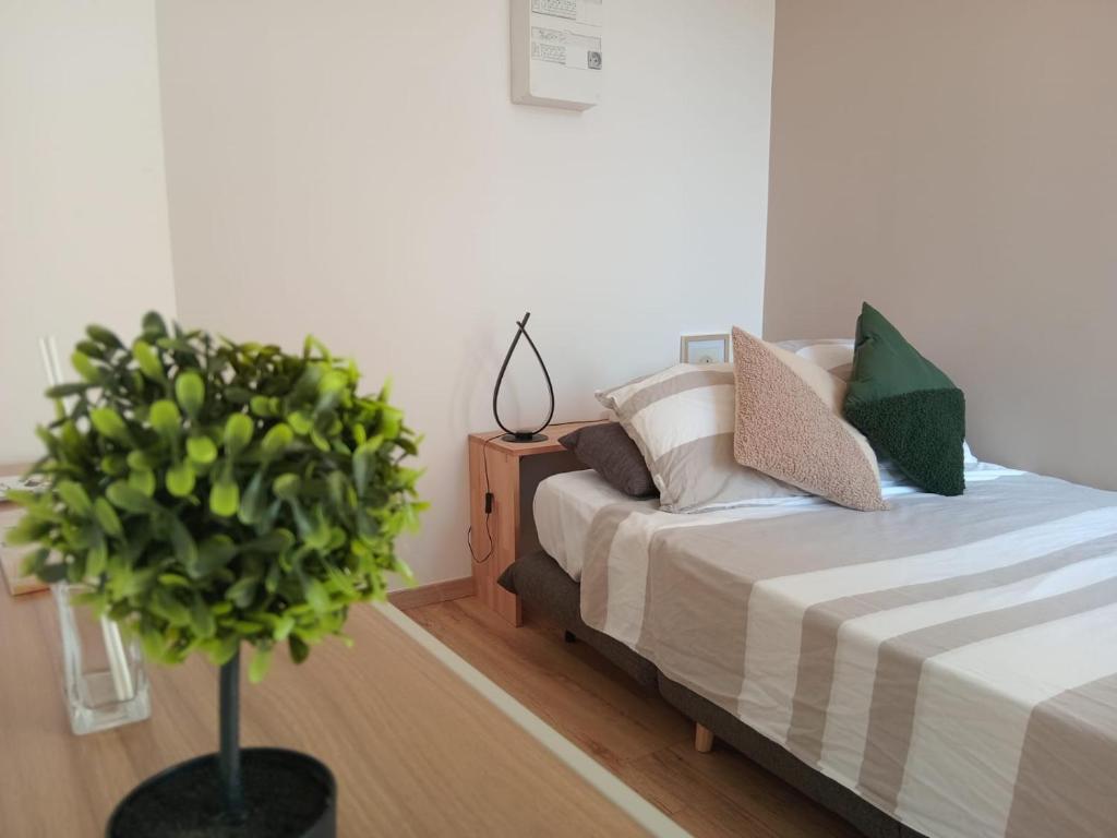 een slaapkamer met een bed en een potplant bij Les Apparts de Marmande - Petit Cocon en ville in Marmande