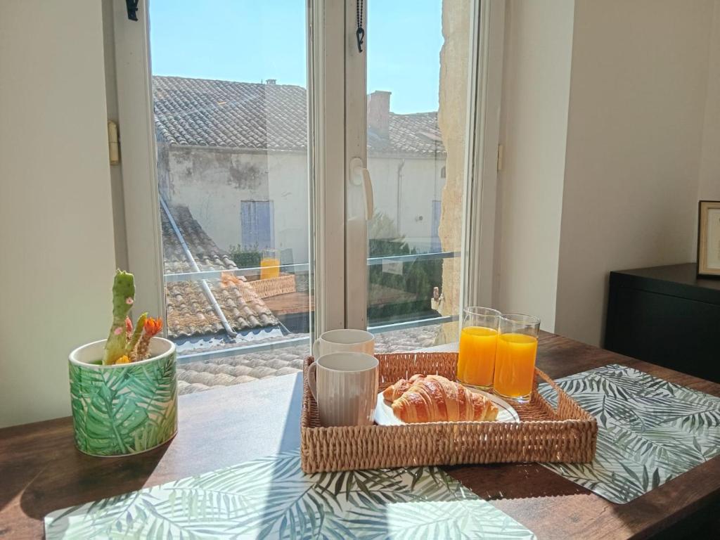 a table with a tray of food and two glasses of orange juice at Les Apparts de Marmande - Petit Cocon en ville in Marmande