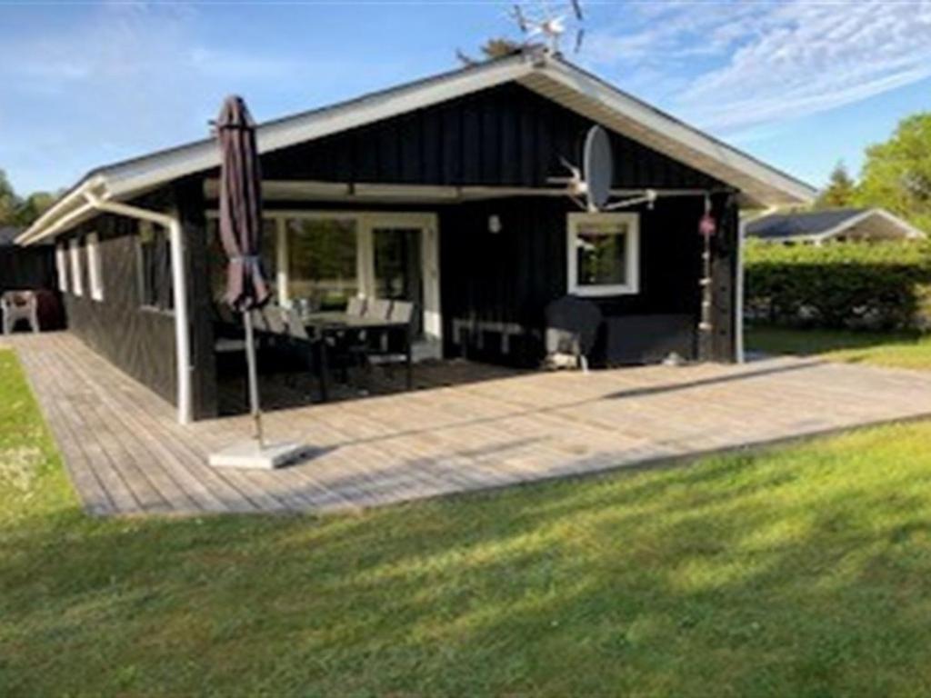 a black house with an umbrella and a patio at Holiday Home Inan - 300m from the sea by Interhome in Hals
