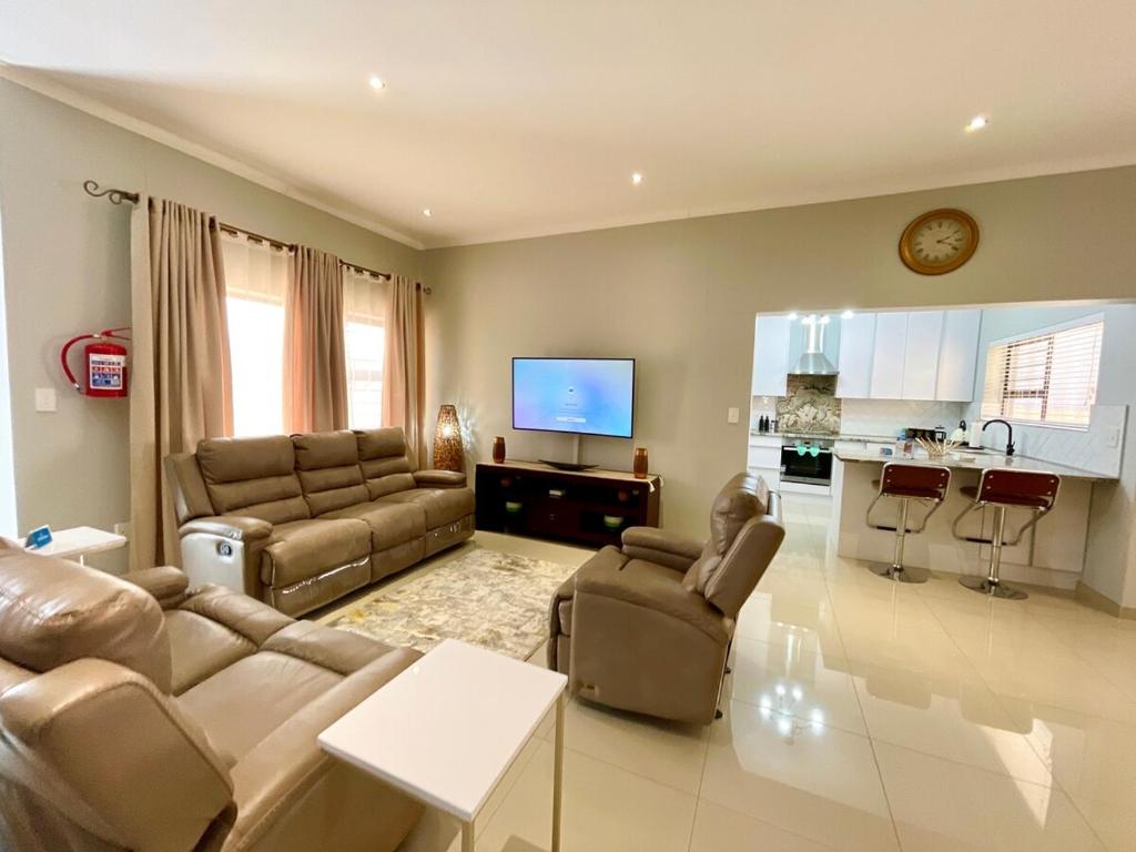 ein Wohnzimmer mit Couch und Fernseher und eine Küche in der Unterkunft Omuhama Ocean Escape in Mondesa