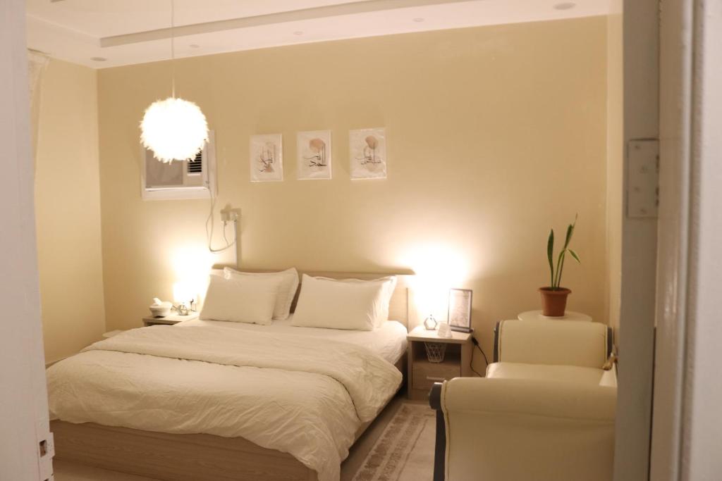 a bedroom with a bed and two white chairs at HOMEY iNN in Al Madinah