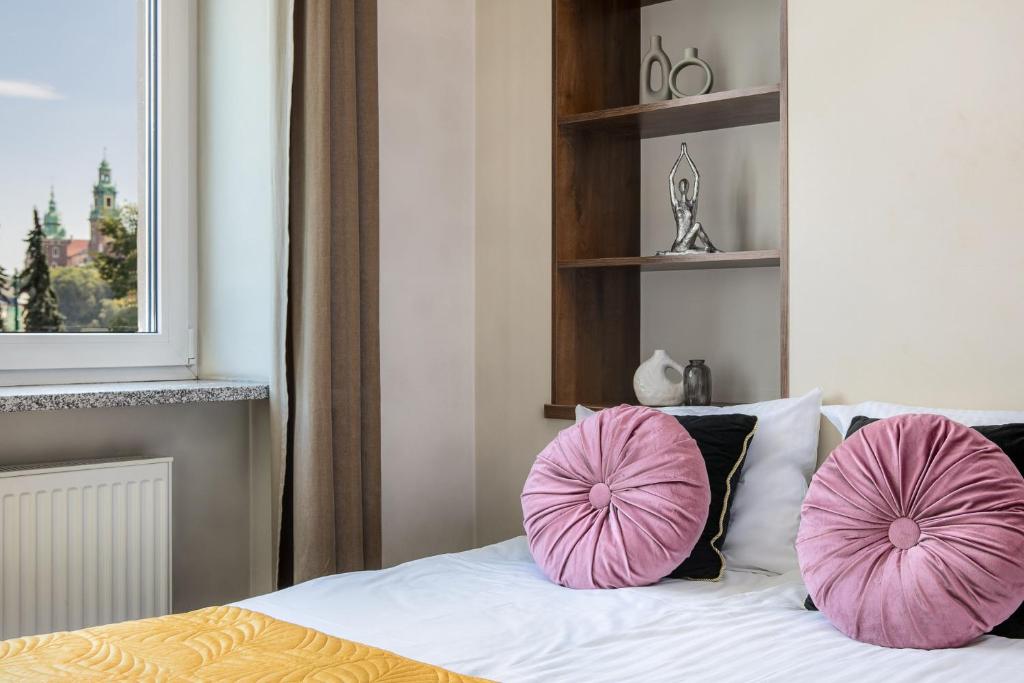 two pink pillows on a bed in a bedroom at Wavelo Apartments in Kraków