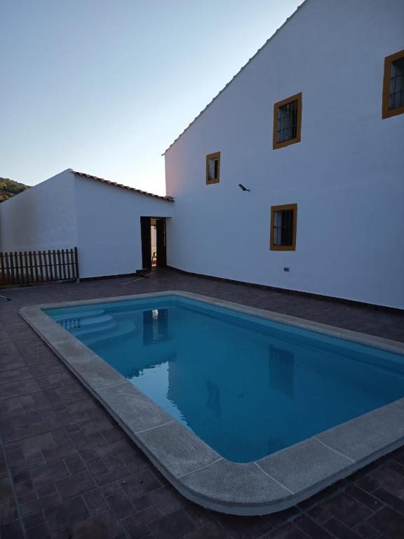 a swimming pool in front of a white building at Casa Rural Cortijo Torres in La Parra