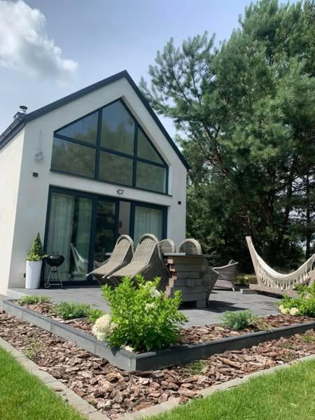 a house with a bunch of chairs in a yard at NAD JEZIORAMI Niedźwiady in Kolonia Pawłówek