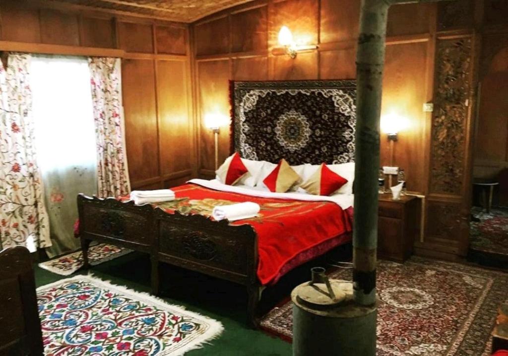 une chambre avec un grand lit avec des draps et des oreillers rouges dans l'établissement T luxury Heritage houseboat, à Srinagar