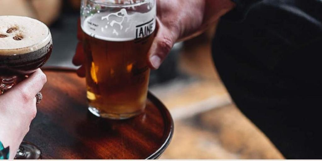 a person holding a glass of beer on a table at The Filly Inn in Brockenhurst