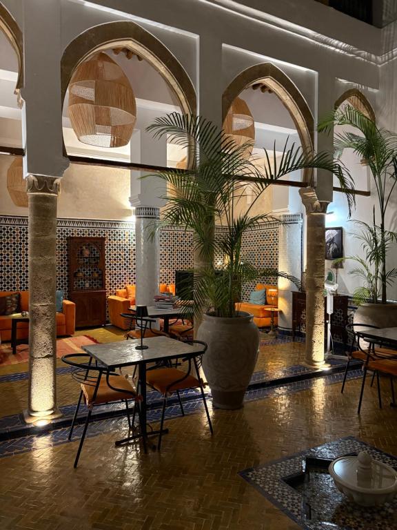 a hotel lobby with tables and chairs and a fireplace at Riad Azula in Salé