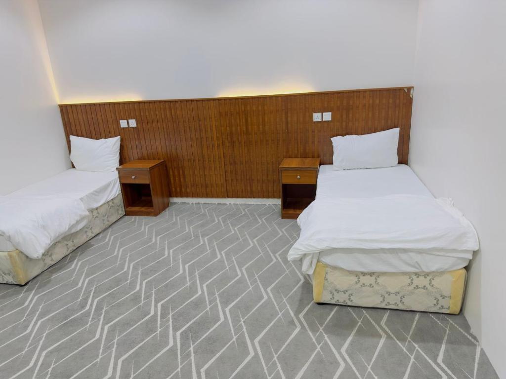 a room with two beds and two night stands at نزل حياة طيبة للنزل السياحة in Al Nawārīyah