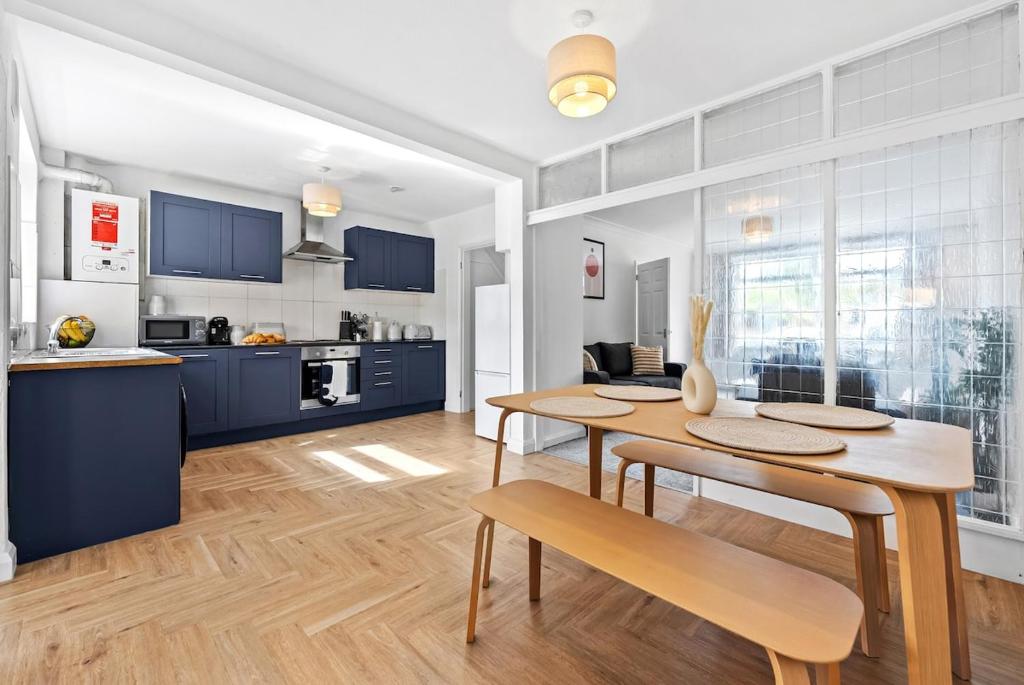 a kitchen and dining room with blue cabinets and a table at NEW! Spacious 4 bedroom 4BR with Private Parking near city Centre in Leamington Spa