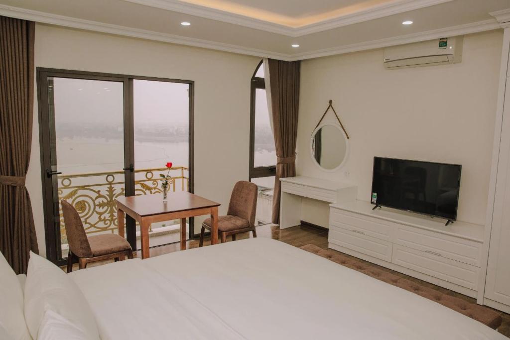a bedroom with a bed and a television and a table at Queenie Hotel in Hai Phong