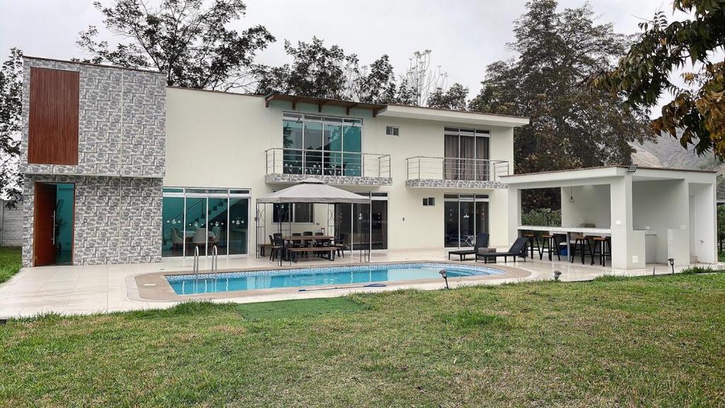 ein Haus mit einem Swimmingpool davor in der Unterkunft Casa campo las Pecanas Huaral 