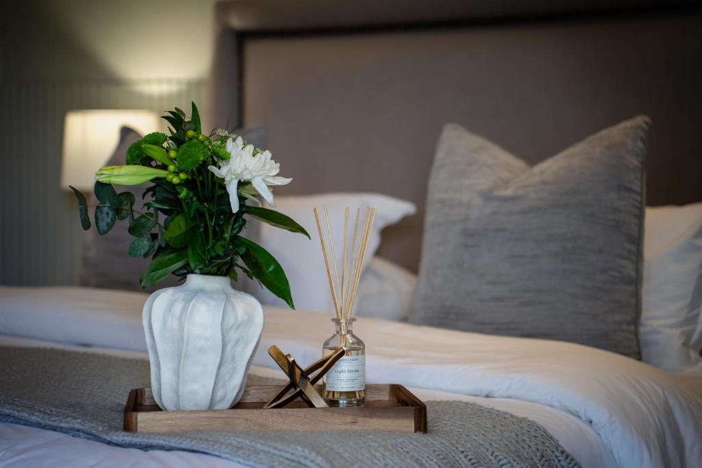 a table with a vase of flowers on a bed at Kénōsis Guestfarm - Room 1 in Springbok