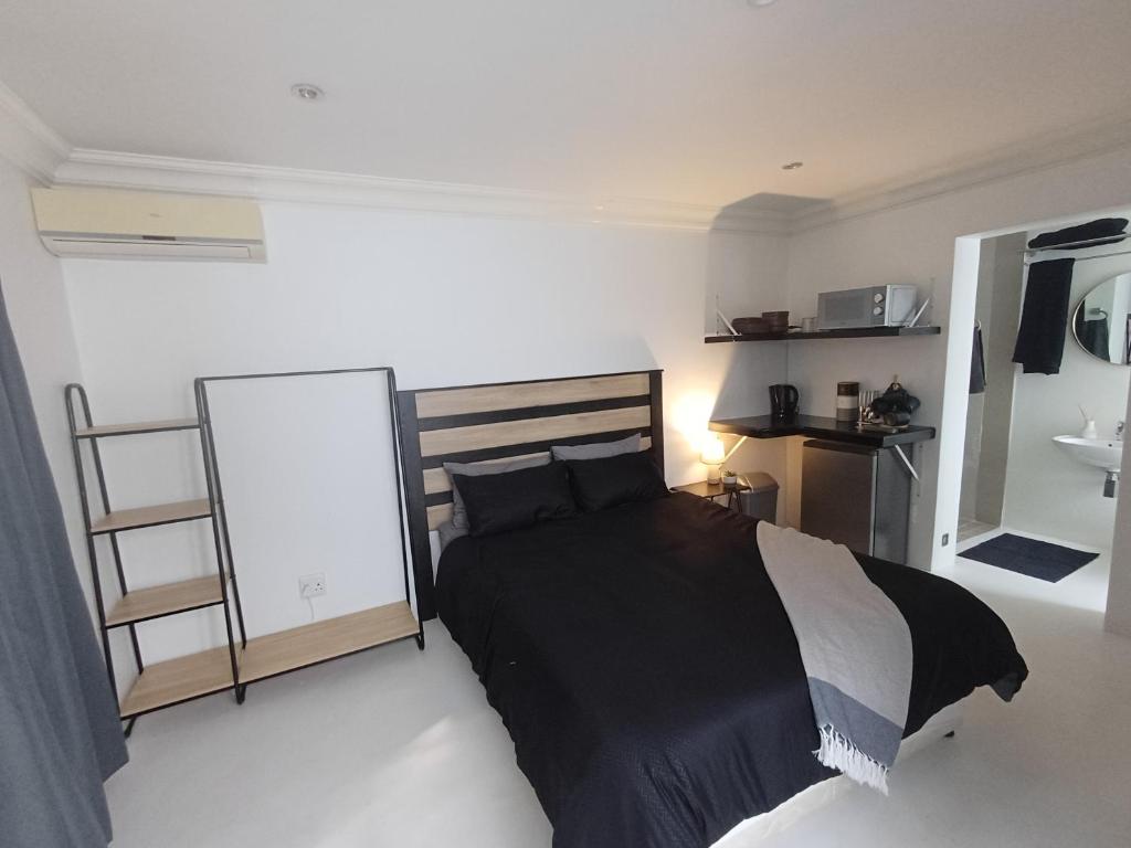 德班Rosetta Cottage的一间卧室配有一张黑色的床和镜子