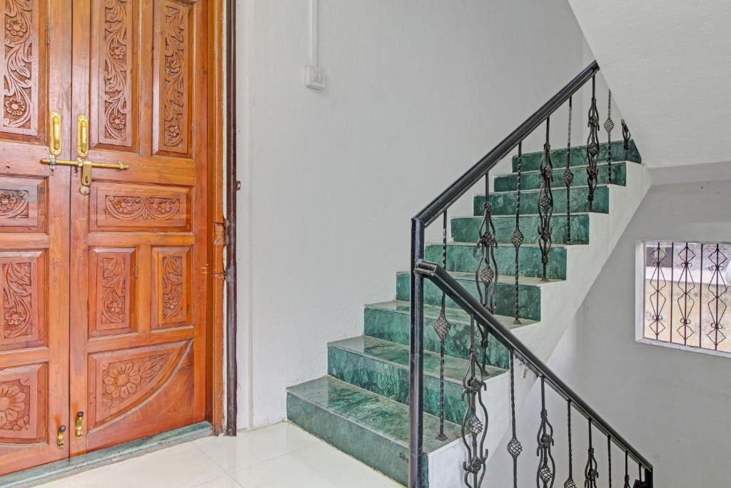 a staircase with a wooden door and green stairs at Hotel O Star in Kharadi