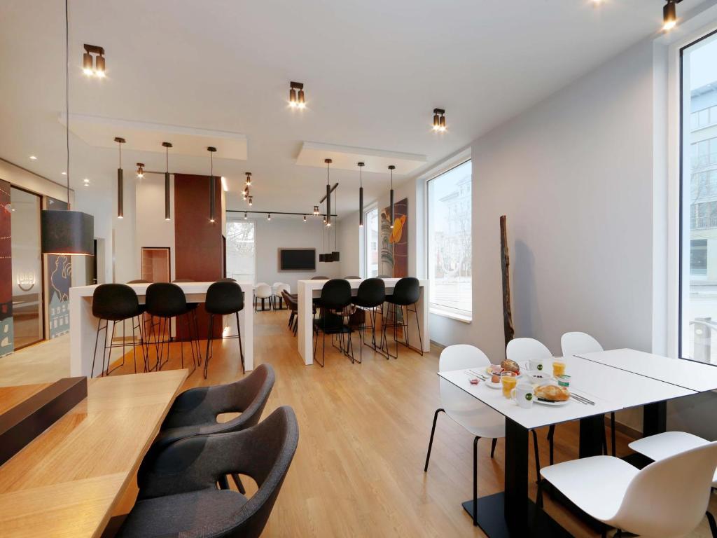 comedor y sala de estar con mesas y sillas blancas en B&amp;B HOTEL Frankfurt-Oder, en Frankfurt de Oder