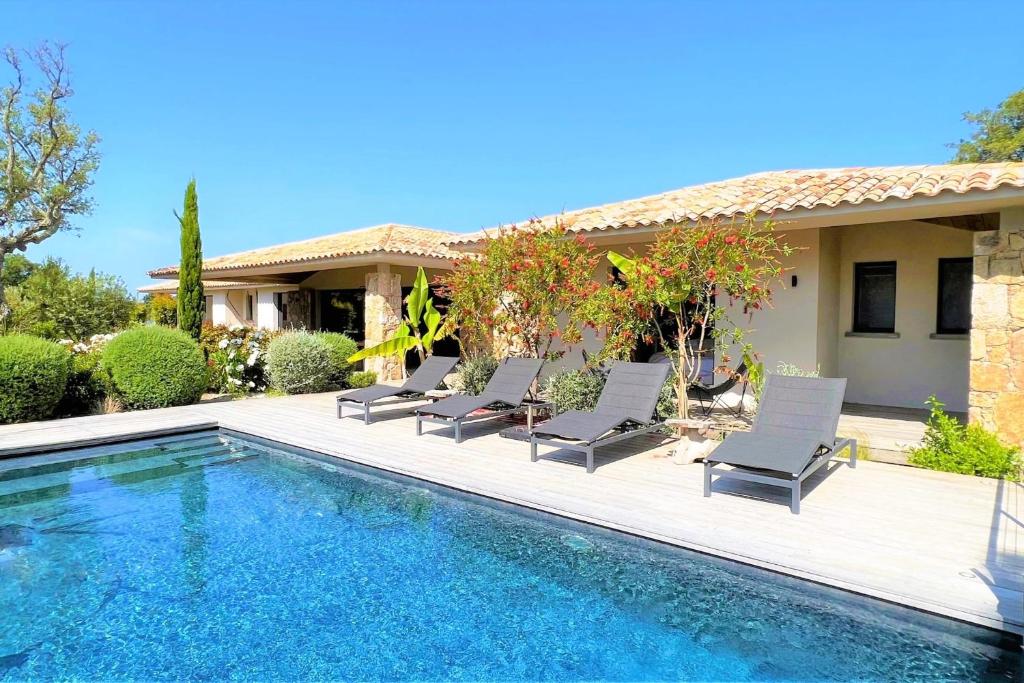 a villa with a swimming pool and lounge chairs at Villa Pignotulli Di Cirendinu in Sainte-Lucie de Porto-Vecchio