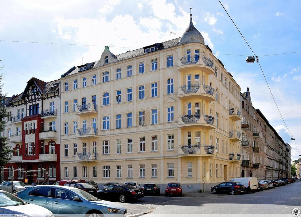 a large yellow building with cars parked in front of it at Apartment Rozbrat 5 in Wrocław